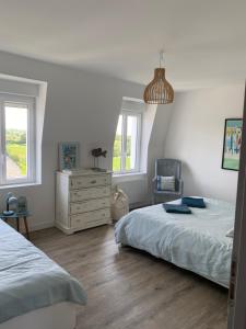 a bedroom with two beds and a dresser at La Maison du Hommeel in Gratot