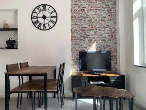 a dining room with a desk with a television and a clock at L'épicurieux in Lille
