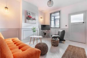 ein Wohnzimmer mit einem orangenen Sofa und Stühlen in der Unterkunft Zest Homes 34 Barton Road in Hereford