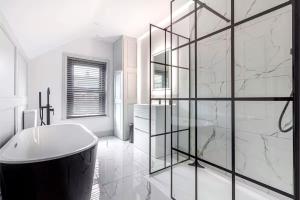 ein weißes Bad mit einer Badewanne und einer Glaswand in der Unterkunft Zest Homes 34 Barton Road in Hereford