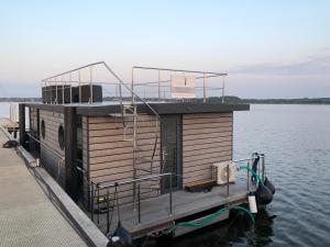 石勒苏益格Hausboot Fjord Nordstern mit Dachterrasse in Schleswig的船屋船被绑在水面上的码头上
