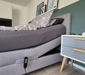 a gray couch with a remote control next to a bed at Ferienwohnung Villa Grimm in Burbach +15 photos