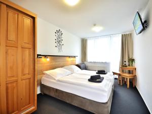 sypialnia z dużym białym łóżkiem i drewnianymi drzwiami w obiekcie Hotel Resort Luna w mieście Ledeč nad Sázavou +34 zdjęcia