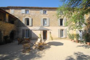 a patio with chairs and an umbrella in front of a building at Les Guillaume Rey in Oppède