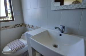 ヌサドゥアにあるRumah Gadang Bali Apartmentsの洗面台とトイレを備えた白いバスルーム +7枚の写真