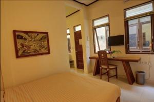 ヌサドゥアにあるRumah Gadang Bali Apartmentsのベッドと机とテーブルのある寝室