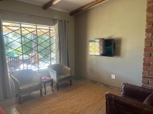 a living room with two chairs and a window at The Grove in Potchefstroom