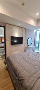 a bedroom with a large bed with a flat screen tv at Minimalist Designer Style Apartement Branz BSD 1BR in Samporo