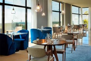 a restaurant with tables and chairs and windows at NH Sintra Centro in Sintra