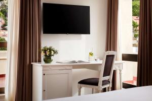 a desk with a chair and a television on a wall at NH Sintra Centro in Sintra