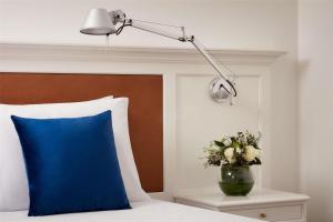 a bed with a blue pillow and a lamp on a table at NH Sintra Centro in Sintra +32 photos