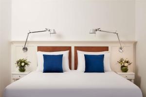 a bedroom with a white bed with blue pillows at NH Sintra Centro in Sintra