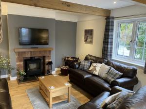 a living room with leather furniture and a fireplace at Barn Cottage, Minehead in Minehead