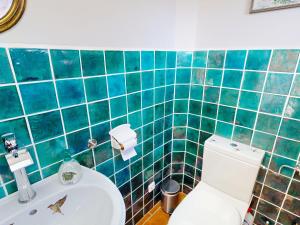 a bathroom with a toilet and a green tiled wall at Marktplatz Traunsee LAKE View in Gmunden