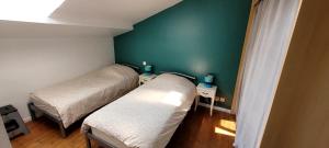 a bedroom with two beds and a green wall at Le Duplex Charentais in Saint-Jean-dʼAngély