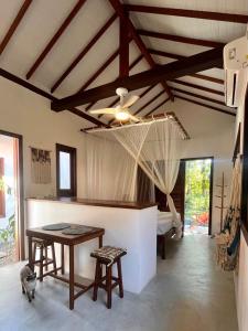 a living room with a table and chairs and a bed at Chalés do Maestro in Ilha de Boipeba