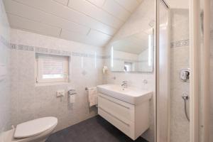 a white bathroom with a sink and a toilet at Micheli Hermann Obst- und Weinbauernhof mit "Südtirol Alto Adige Guest Pass - Mobilcard" in Caldaro +22 photos
