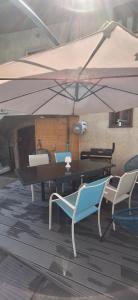 a table and chairs under an umbrella on a deck at "Le Glandon"- Parenthèse de charme in Saint Avre la Chambre