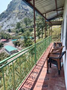 a balcony with two chairs and a view of a mountain at Corn Village Cottage in Lakhwār