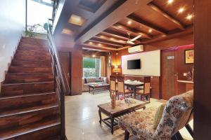 a living room with a staircase and a table and chairs at SaffronStays Barlowganj Villa in Mussoorie +30 photos