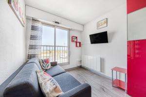 un soggiorno con un divano e una grande finestra di Appartement face à la mer a Soulac-sur-Mer