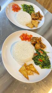 two plates of food with rice and vegetables on a table at Oeseli Beach Bungalow in Pulau Helihana +9 photos