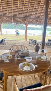 a wooden table with plates of food on it at Oeseli Beach Bungalow in Pulau Helihana