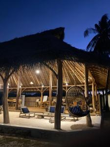 a straw umbrella and chairs in a pavilion at Oeseli Beach Bungalow in Pulau Helihana