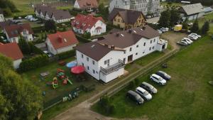 a large white house with cars parked in a yard at Noce i dnie in Białogóra