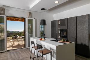 a kitchen with a white counter and chairs and a large window at Dimora degli Ulivi 10 Emma Villas in Noto
