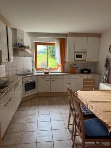 a kitchen with white cabinets and a table and a window at Lisa & Gretl's Alpen-Panorama Chalet Saalfelden - 10 Min nach Zell am See in Saalfelden am Steinernen Meer