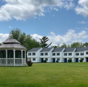 a row of white buildings with a gazebo in a field at Acadia Village Resort in Ellsworth