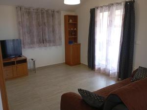 a living room with a couch and a television at Nika's Sea View Oasis in Seget