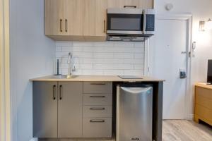una pequeña cocina con lavavajillas de acero inoxidable en Exclusive Room - Hotel Le Cavalier by M11, en Quebec