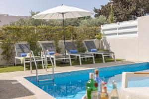 a pool with chairs and an umbrella next to a swimming pool at Milan's Mythical Villa in Paralimni