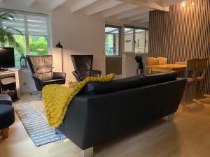 a living room with a black couch with a yellow blanket at heerlijk vakantie huis Lovely holiday home in Lanaken