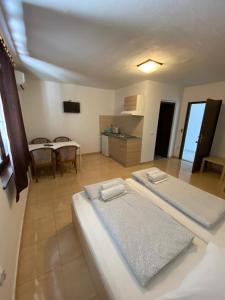 two beds in a room with a table and a kitchen at Apartments Deli in Vrsi +26 photos