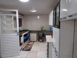 a kitchen with white appliances and a white floor at Casa Recanto do Vale Condominio in Guapimirim