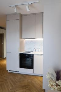 a kitchen with white cabinets and a black appliance at Apartament Valentino Bussines Haven & Family in Kielce