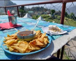a plate of chips on a table with a bowl of food at Corn Village Cottage in Lakhwār +21 photos