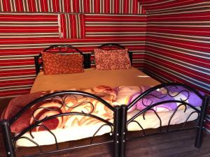 Cama pequeña en habitación con paredes a rayas en Salem Rum Tours & Camp, en Wadi Rum 13 fotos más