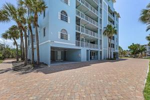 Un gran edificio blanco con palmeras delante. en Fun and Magical Beach Escape - Amazing Beach Condo - Roelens, en Fort Myers Beach