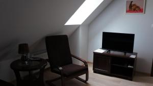 uma sala de estar com uma cadeira e uma televisão de ecrã plano em GOŚCINIEC NAD NARWIĄ - Airport Modlin em Kikoły