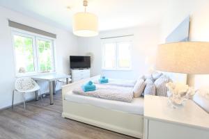 a white bedroom with a bed and a desk at Ferienhaus Stefanie 1 in Langeoog