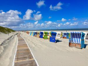 a row of beach chairs on a sandy beach at MeeresZeit in Langeoog