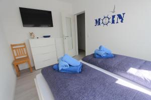 two beds with blue pillows in a room at Lüttje Parl in Langeoog