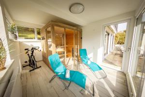 ビショフスハイム・アン・デア・レーンにあるFerienhaus Heimatliebe Rhönのガラステーブルと青い椅子2脚が備わる客室です。 +2枚の写真