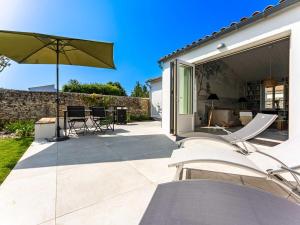 eine Terrasse mit Stühlen und einem Sonnenschirm in der Unterkunft Maison de vacances avec jardin verdoyant à Loix - FR-1-835-25 in Loix