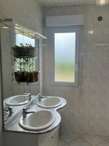 a bathroom with two sinks and a window at Gîtes de la Mouette L'Estran 8 à 9 personnes in Ravenoville