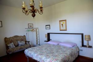 パンツァーノにあるLittle B&B Della Pieveのベッドルーム1室(ベッド1台、椅子、シャンデリア付)